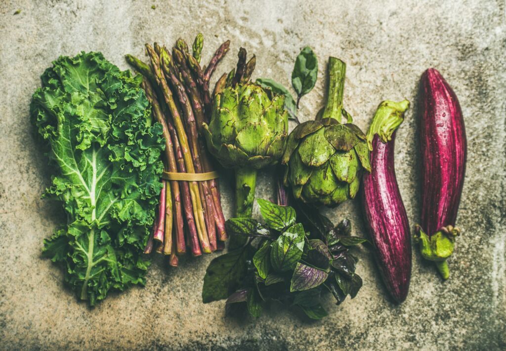 Flat-lay of fresh green and purple vegetables, top view